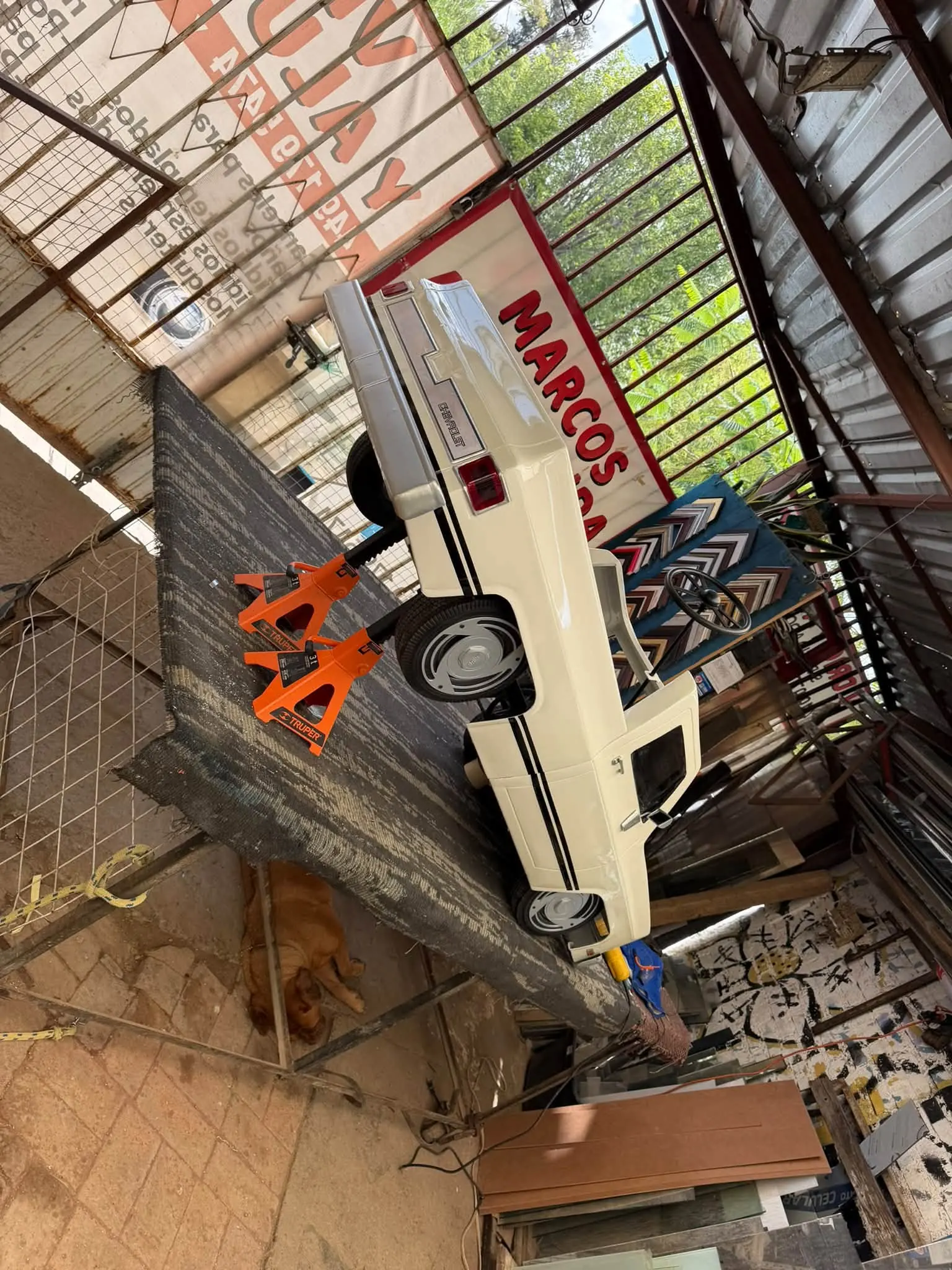 Handcrafted miniature Chevy C10 chassis elevated on workshop stands