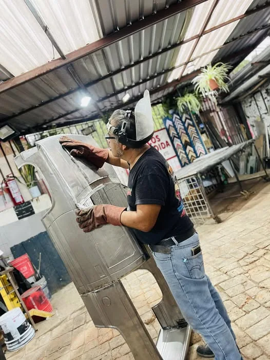 Master artisan hand-shaping and welding raw steel custom miniature body